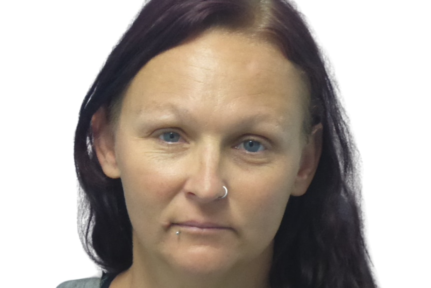 A woman with a nose piercing stares seriously into the camera