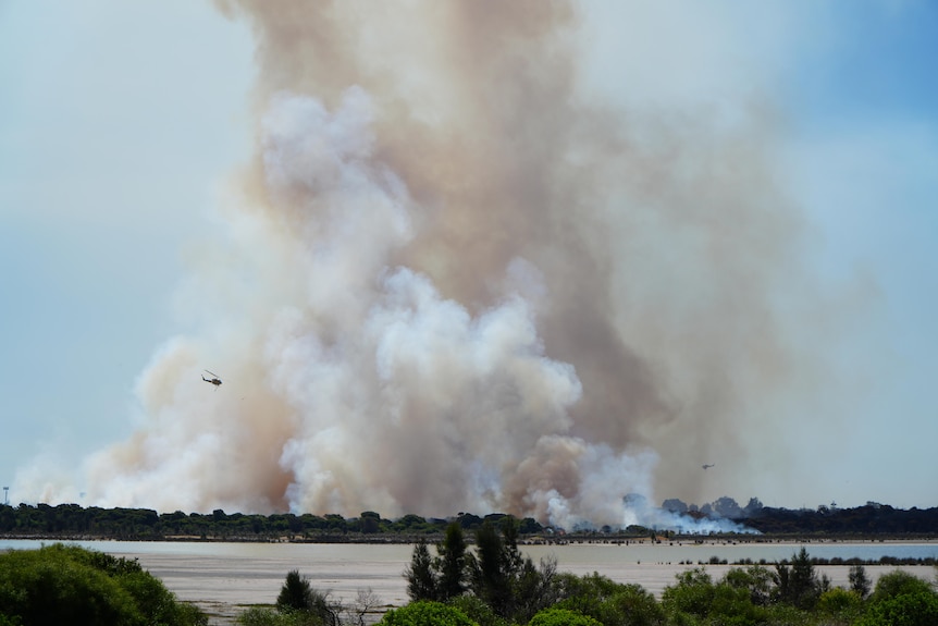 Water bombers fly over a huge plume of smoke