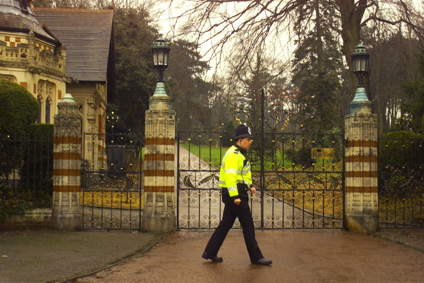 a policeman walks past an ornate gate 