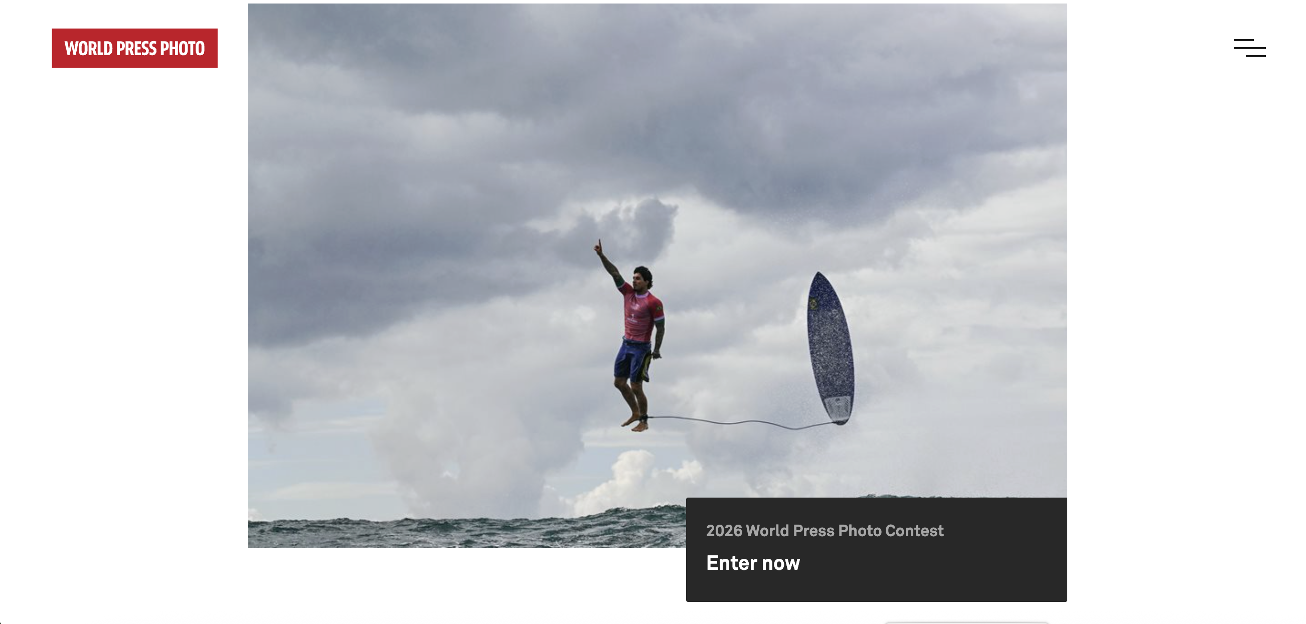 The website for the 2026 World Press Photo Contest, displaying an action shot of a man surfing or paddleboarding, suspended above the water with a surfboard, against a cloudy sky.