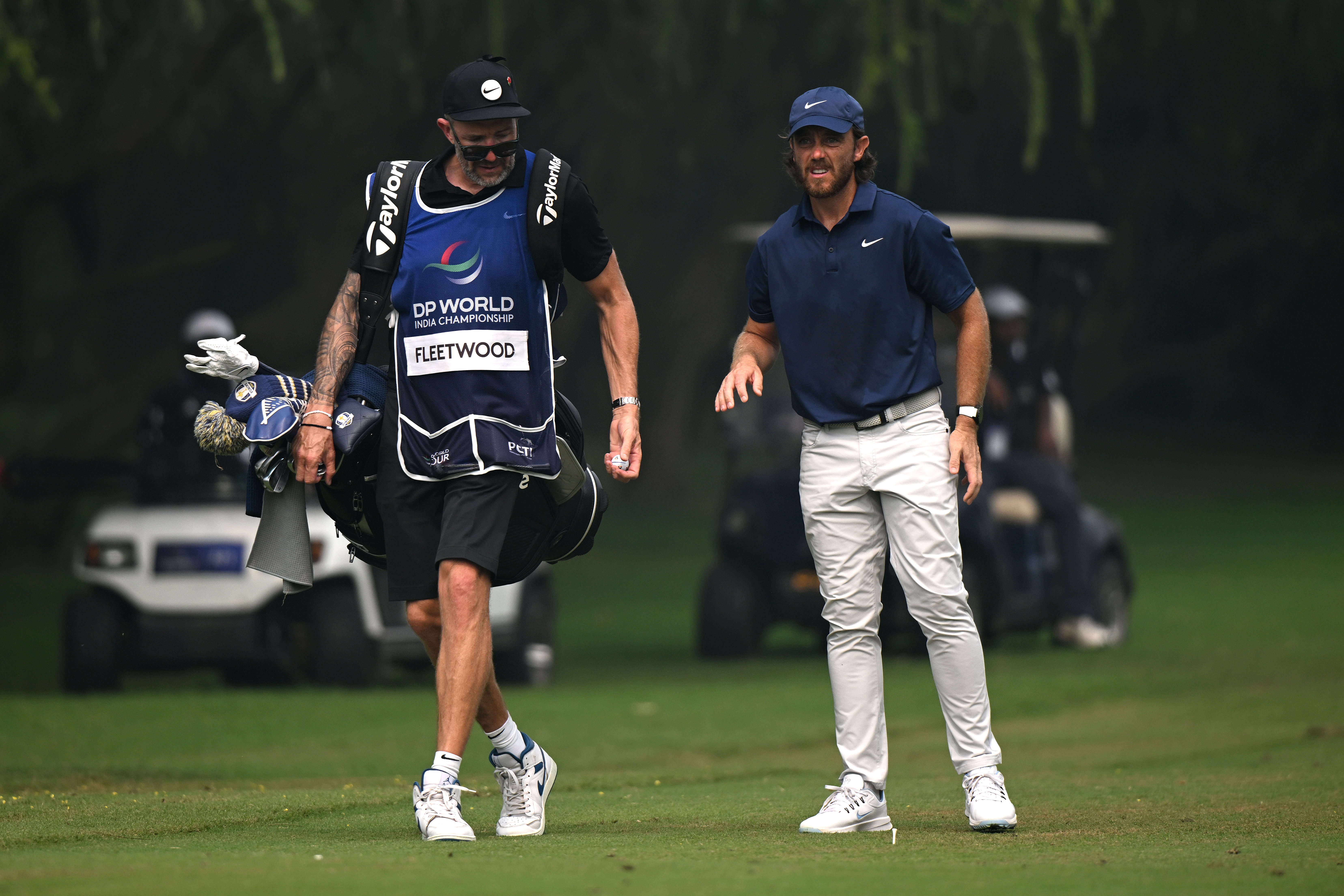 Tommy Fleetwood walks alongside his caddie