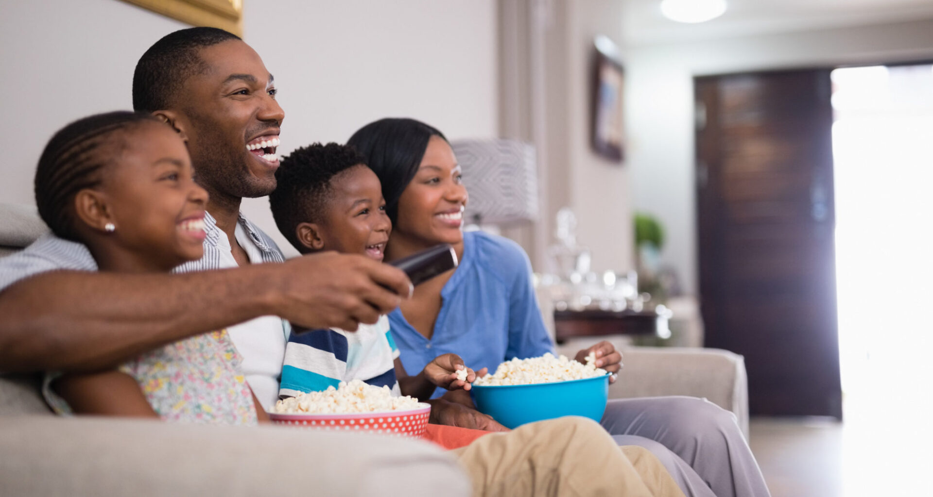 Cheerful family having popcorn while watching television at home