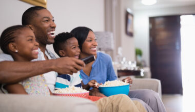 Cheerful family having popcorn while watching television at home