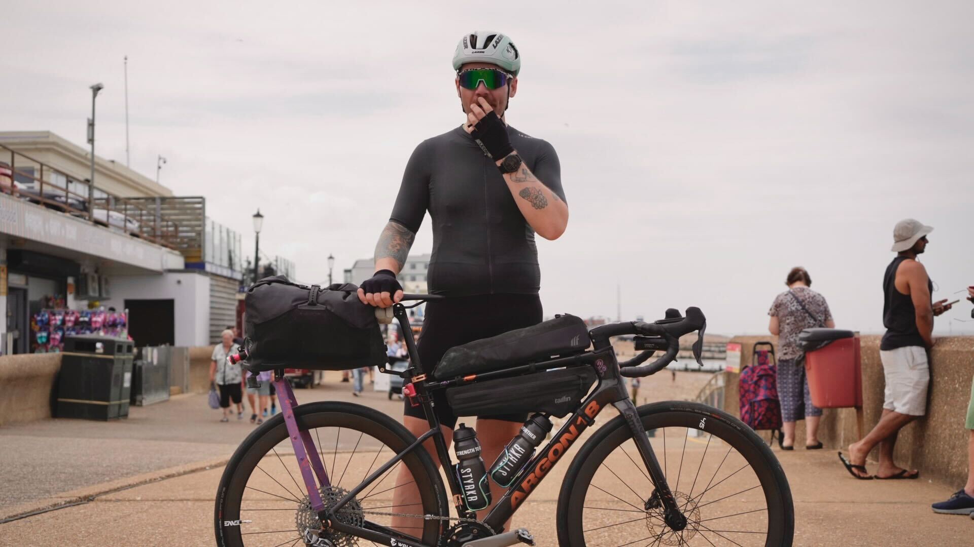 Man stands next to bike on seafront