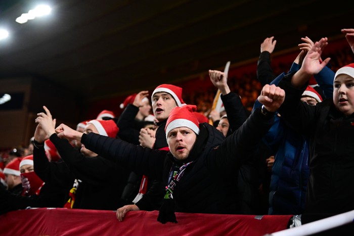 Fans, in Christmas hats, hold their hands up in the air in the stands at the Riverside.