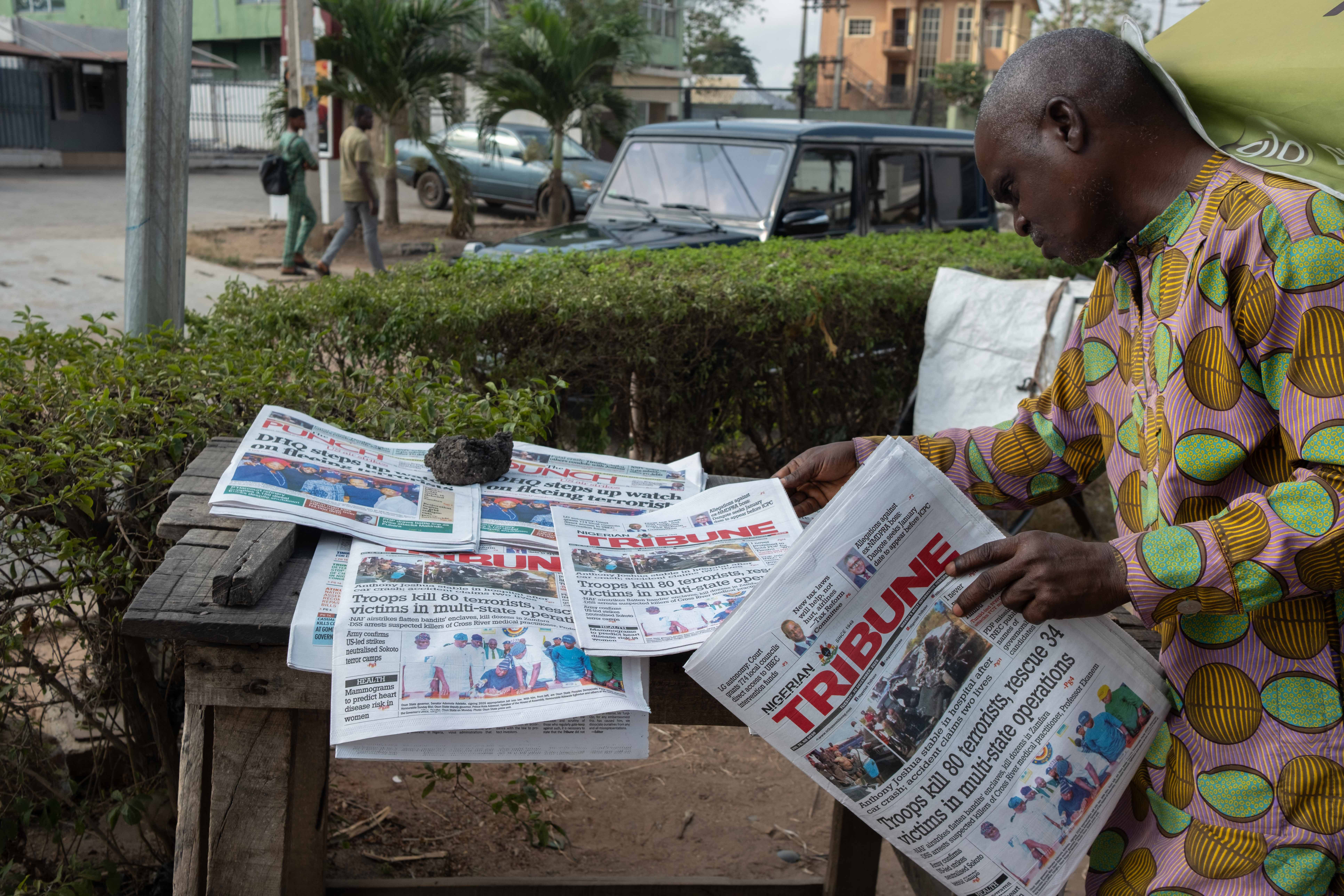 A resident reads newspapers bearing headlines about the car crash