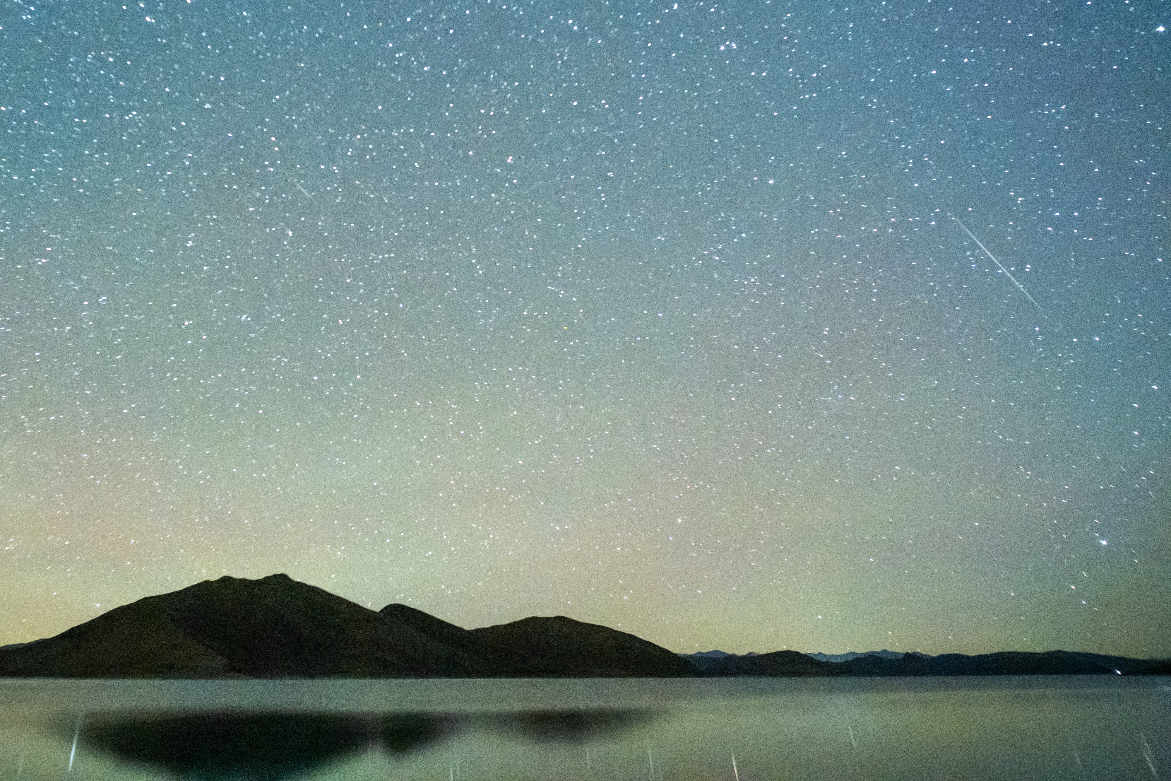 A photo of the Geminids streaking across a starry sky above Yamdrok Lake in Tibet, China.