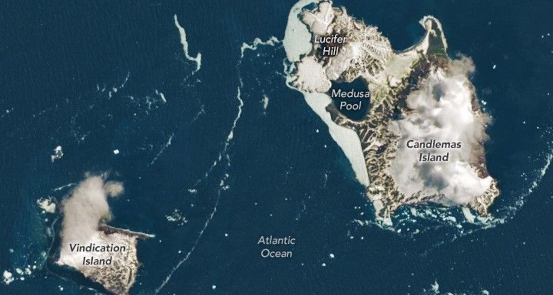 Two large brown and white islands are seen in a dark blue ocean from space with various labels including Vindication Island, Medusa Pool and Lucifer Hill