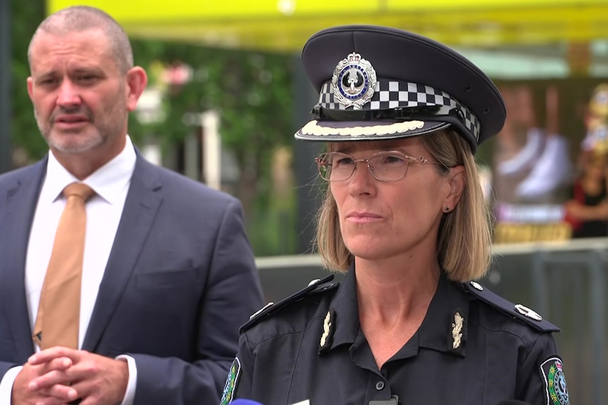 Assistant Commissioner Narelle Kameniar in police uniform stands in front of Kyam Maher at an open-air tram station