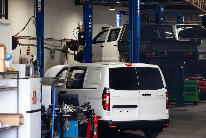 Three cars in a mechanic's shop.