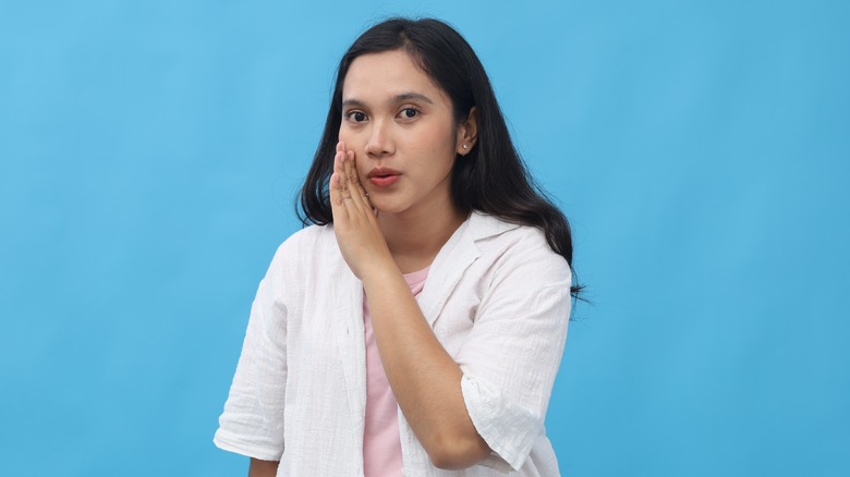 A girl sharing a secret in front of a blue background