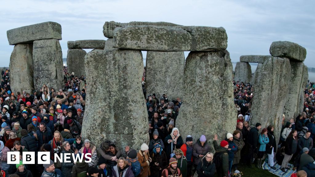 People stand at Stonehenge just after sunrise