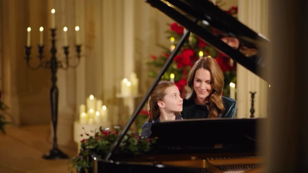 A woman and a girl interacting at a piano in a decorated setting.