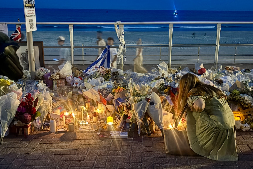mourners light candles and leave flowers along bondi beach promenade