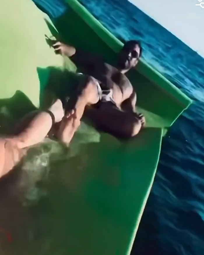 Britney Spears in a bikini and a man relaxing on a yacht deck near ocean water on a sunny day.