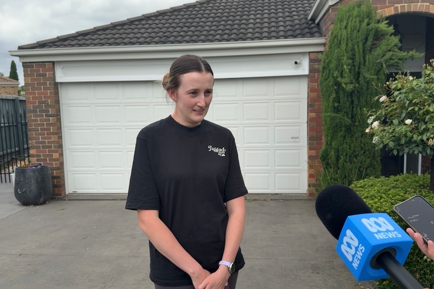 Woman in black t-shirt standing in a drive way looking serious