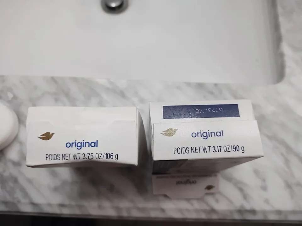 Two bars of Dove soap on a marble countertop, showing different weights: 106g and 90g