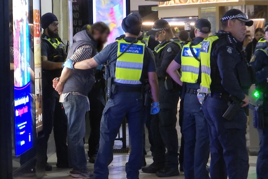 A man being detained by police.