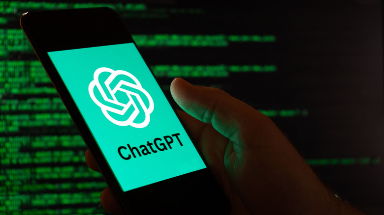 ChatGPT logo on a mobile device infront of a wall of green text