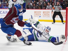Kevin Lankinen, back, makes a glove save of a shot off the stick of Colorado Avalanche centre Ross Colton in the first period