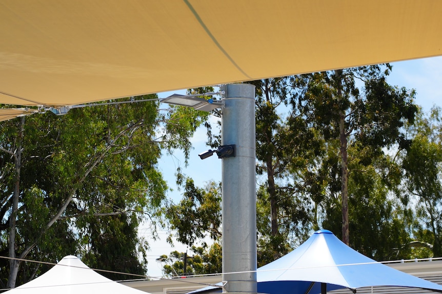 A small camera is mounted to a bracket at a public pool