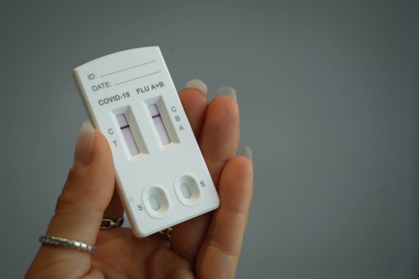 A person with manicured nails holding a RAT test