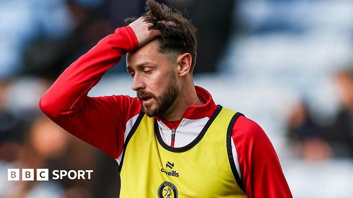 Harry Cornick runs his hand through his hair, dressed in a red training top and a yellow bib