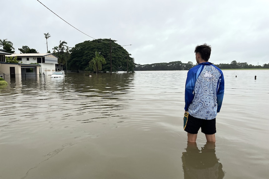 Man stands in flood water during the Ingham 2025 floods.
