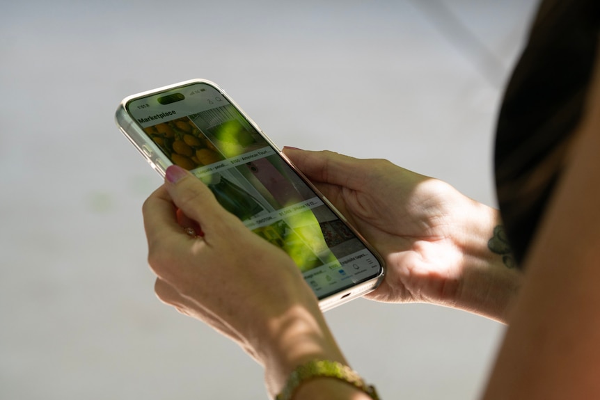 Close-up of a woman in a black dress holding a phone.