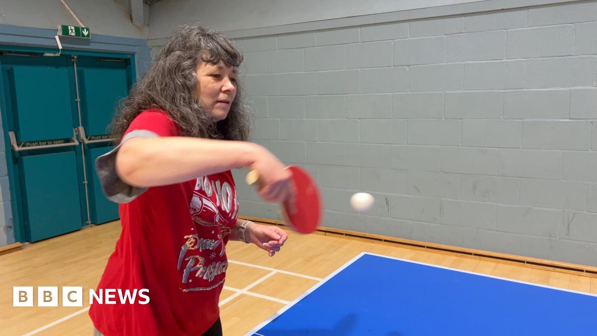 A woman in a red Christmas top returns the ball during a table tennis session organised by Sport in Mind.