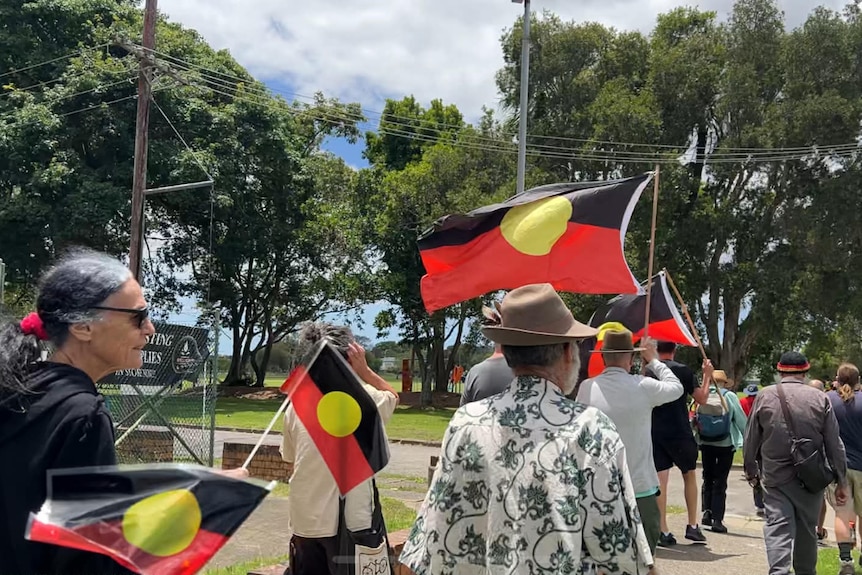 Dozens march and hold Indigenous flags at a rally in Kempsey.