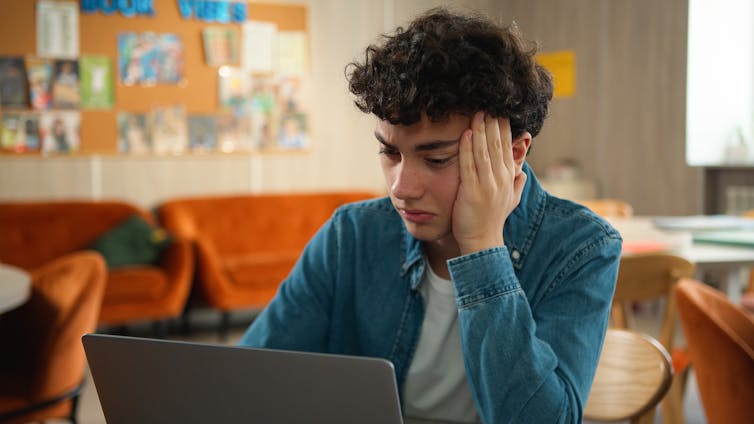 Boy with laptop looking stressed