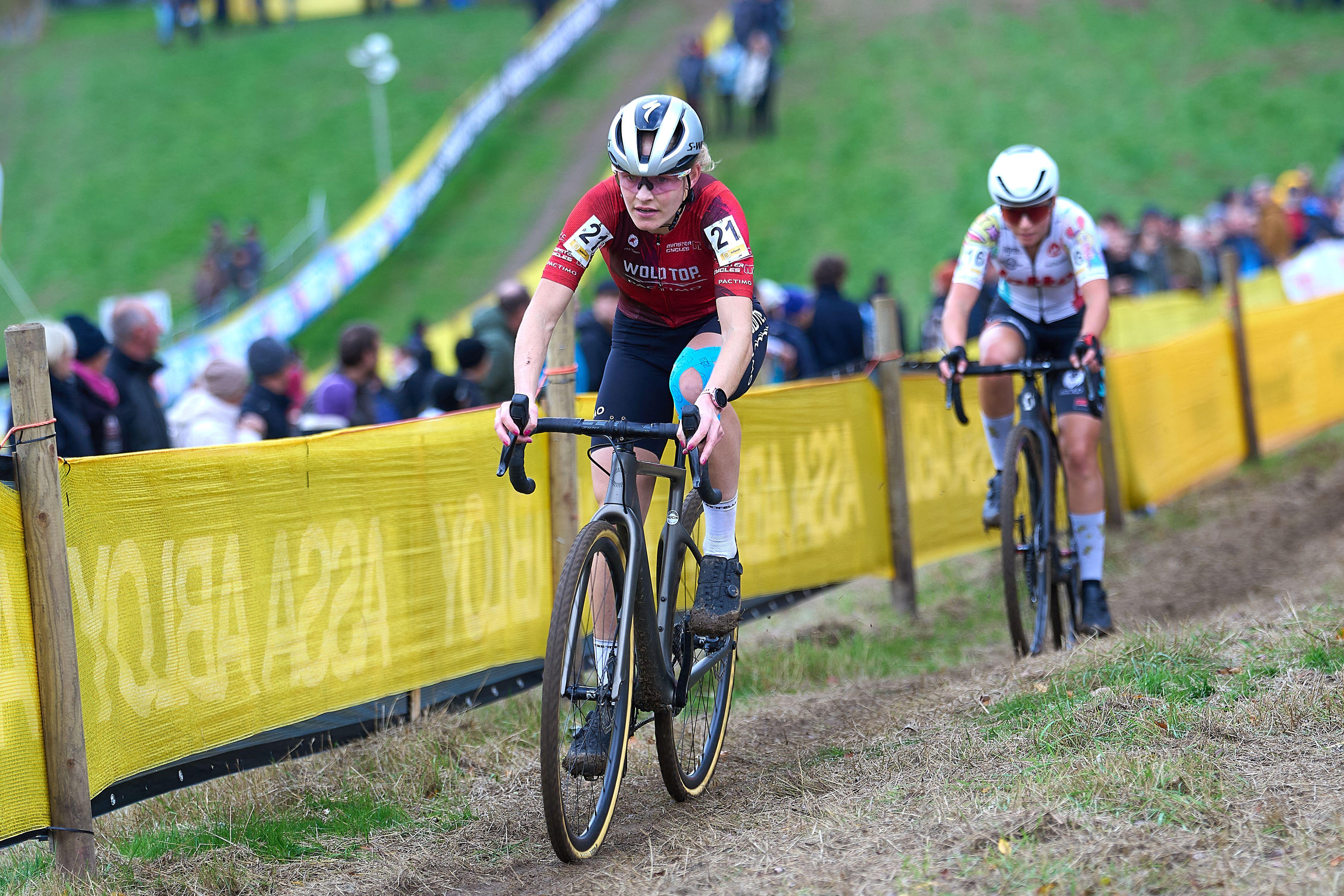 Two female cyclists ride up hill in a cyclocross race