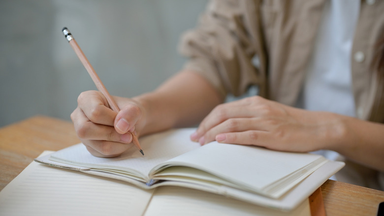 A person doing homework on a notebook and textbook