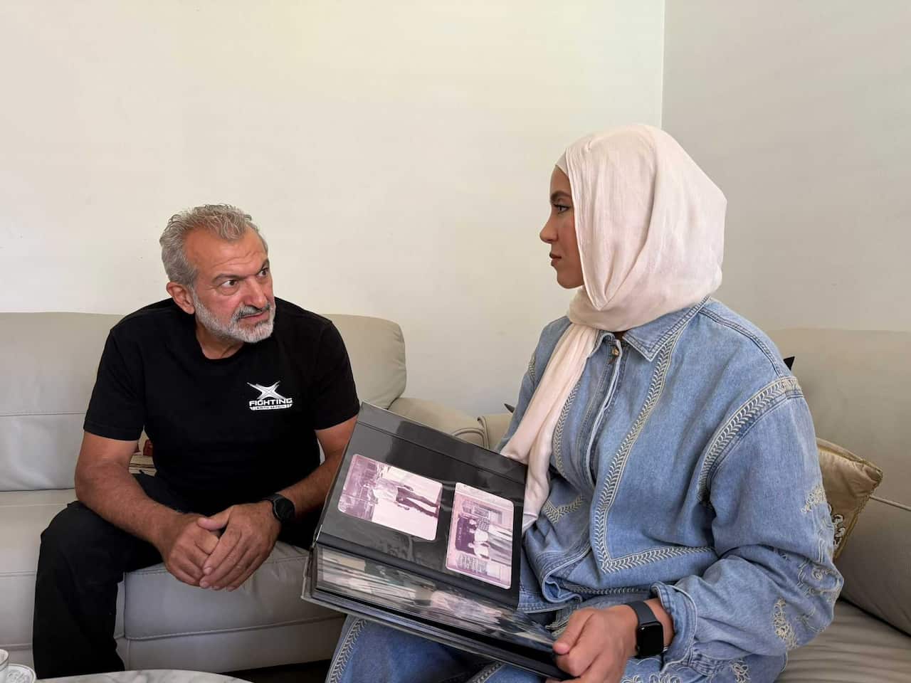 A man on the left sitting beside a woman on the right looking through a photo album.