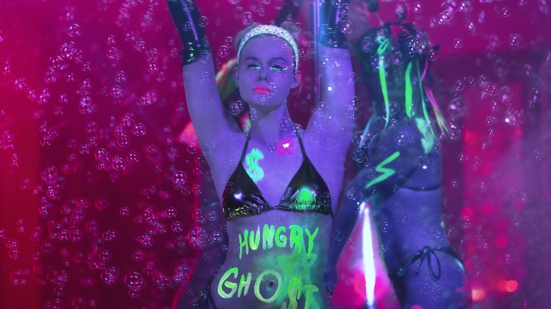 Elle Fanning as Margo wears a bikini and has Hungry Ghost written in glowing paint on her torso in Margo's Got Money Troubles