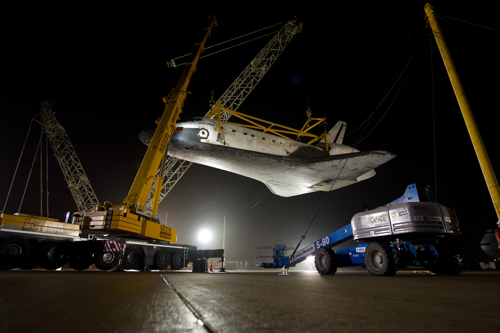 The space shuttle Discovery is suspended from a sling held by two cranes shortly after the NASA 747 Shuttle Carrier Aircraft (SCA) was pushed back from underneath at Washington Dulles International Airport