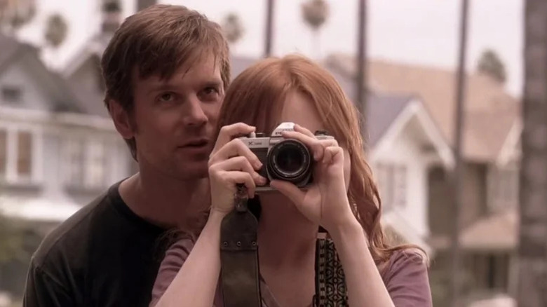 Nate Fisher (Peter Krause) whispers to Claire Fisher (Lauren Ambrose) as she takes a picture on Six Feet Under