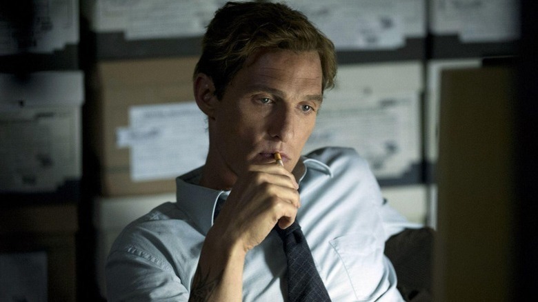 Rust Cohle (Matthew McConaughey) sits pensively with a cigarette in a file room on True Detective