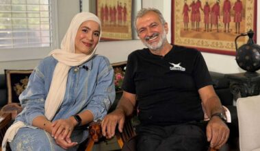 A father and daughter sitting together in their home smiling.