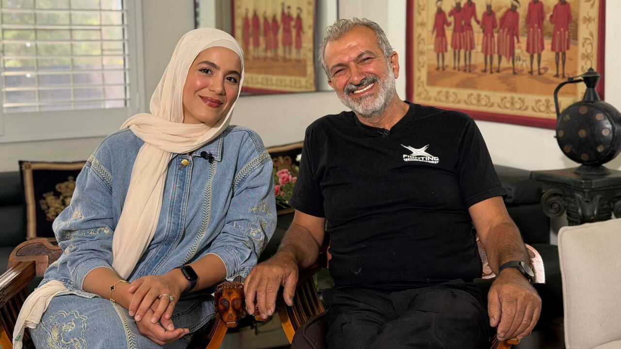 A father and daughter sitting together in their home smiling.