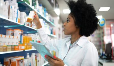 Person checking medicine on a shelf in a pharmacy.
