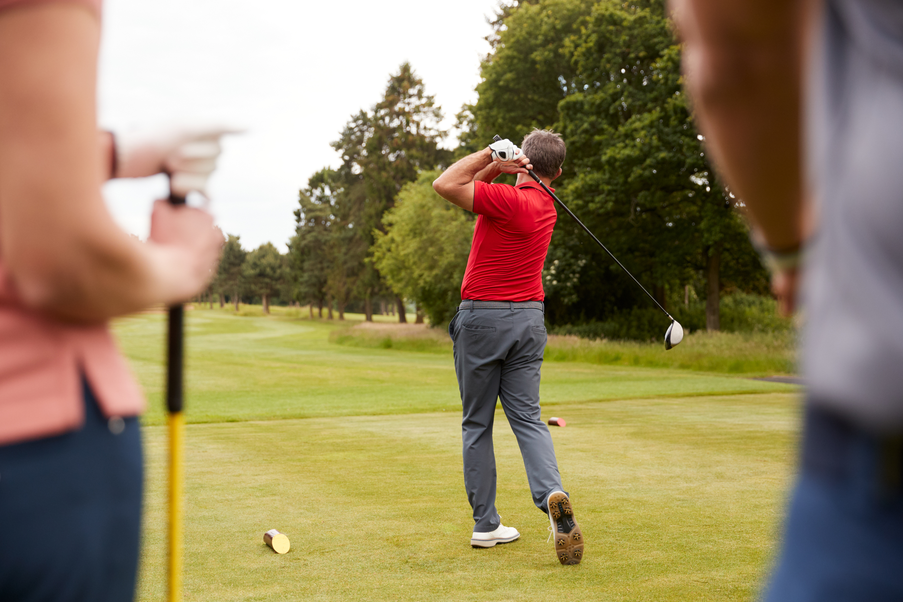 Golf professional demonstrating a tee shot to a group of golfers.