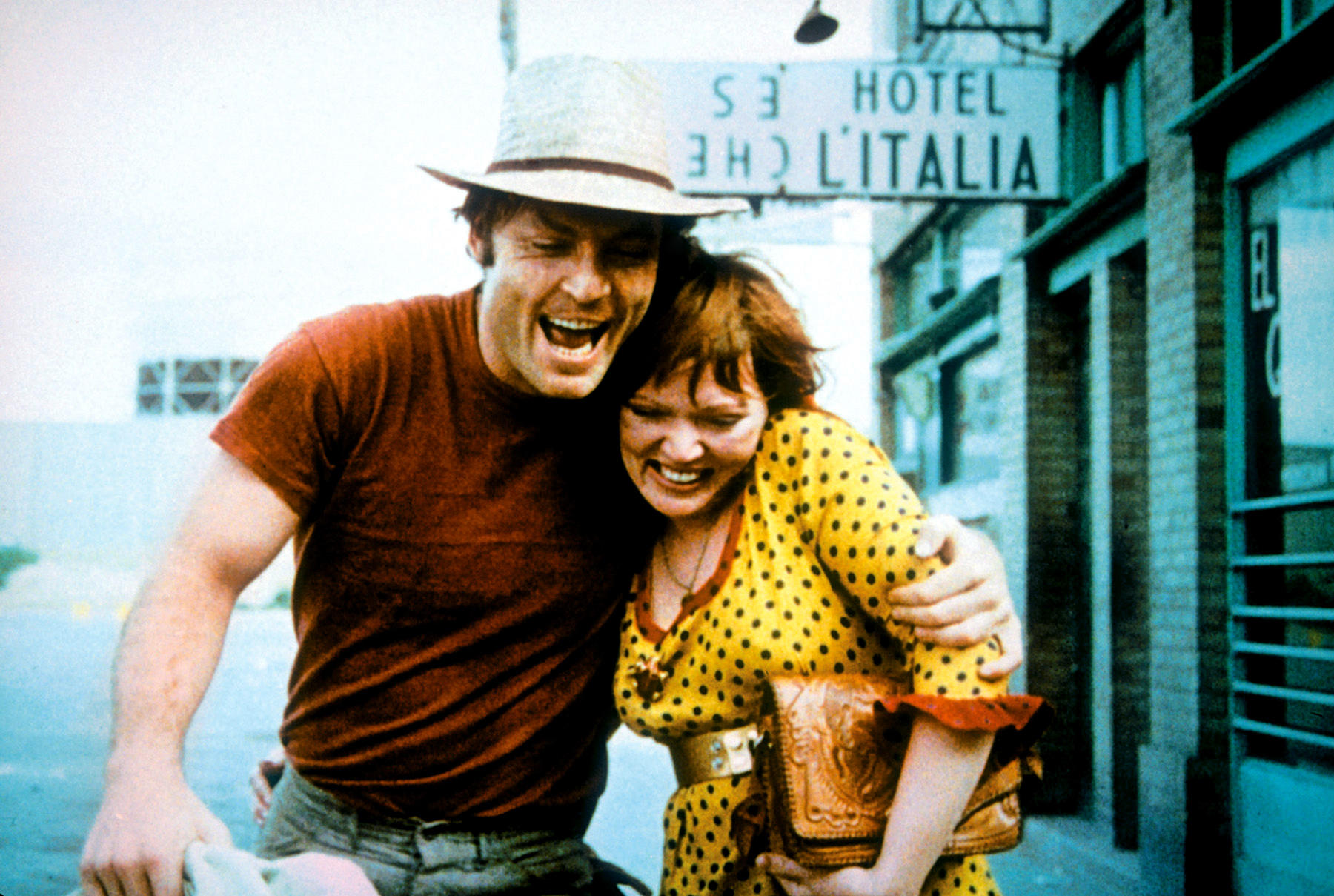 Stacy Keach and Susan Tyrrell laughing together in front of the Hotel L'Italia sign from the film Fat City.