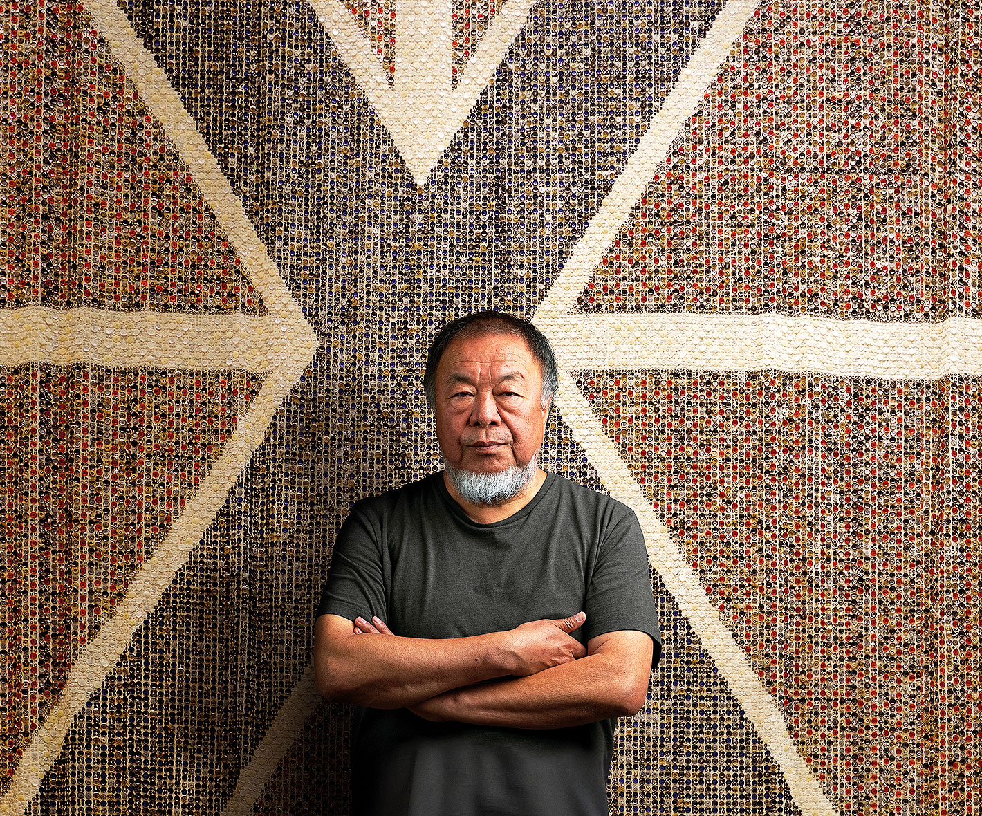 Ai Weiwei posing in front of his artwork made from salvaged buttons.