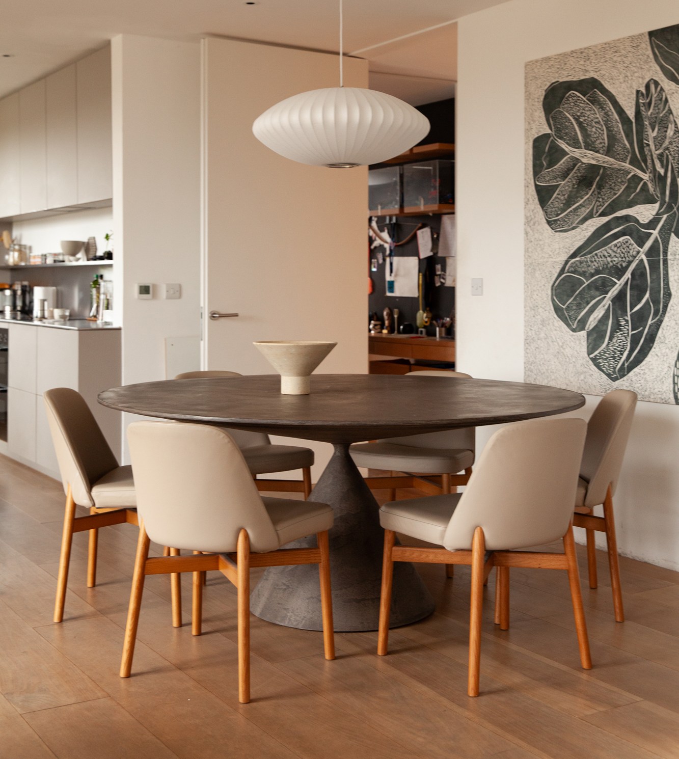 Dining room with a round table, a light fixture, and a wall art.