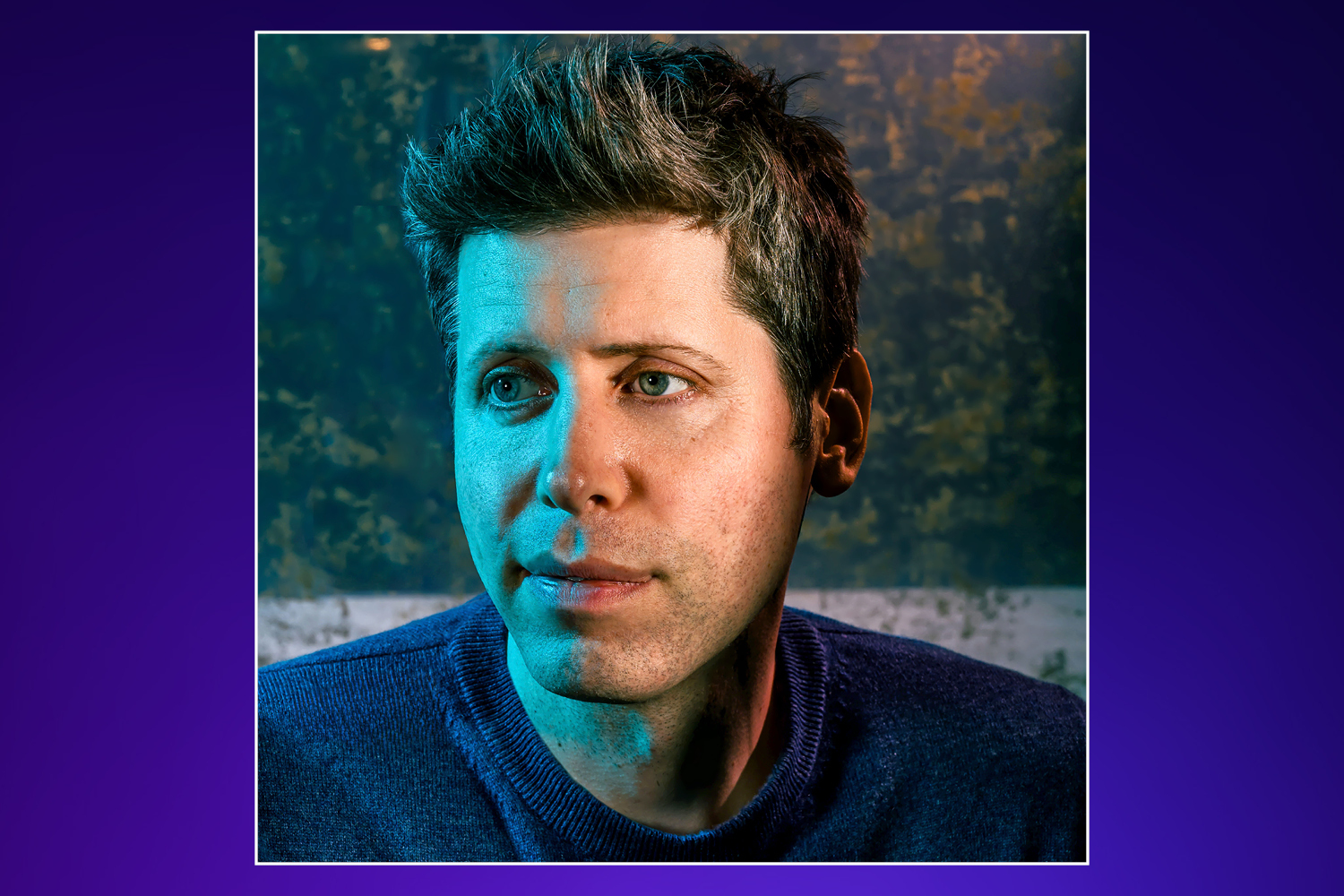 A man in a blue sweater with blue and orange lighting on his face.