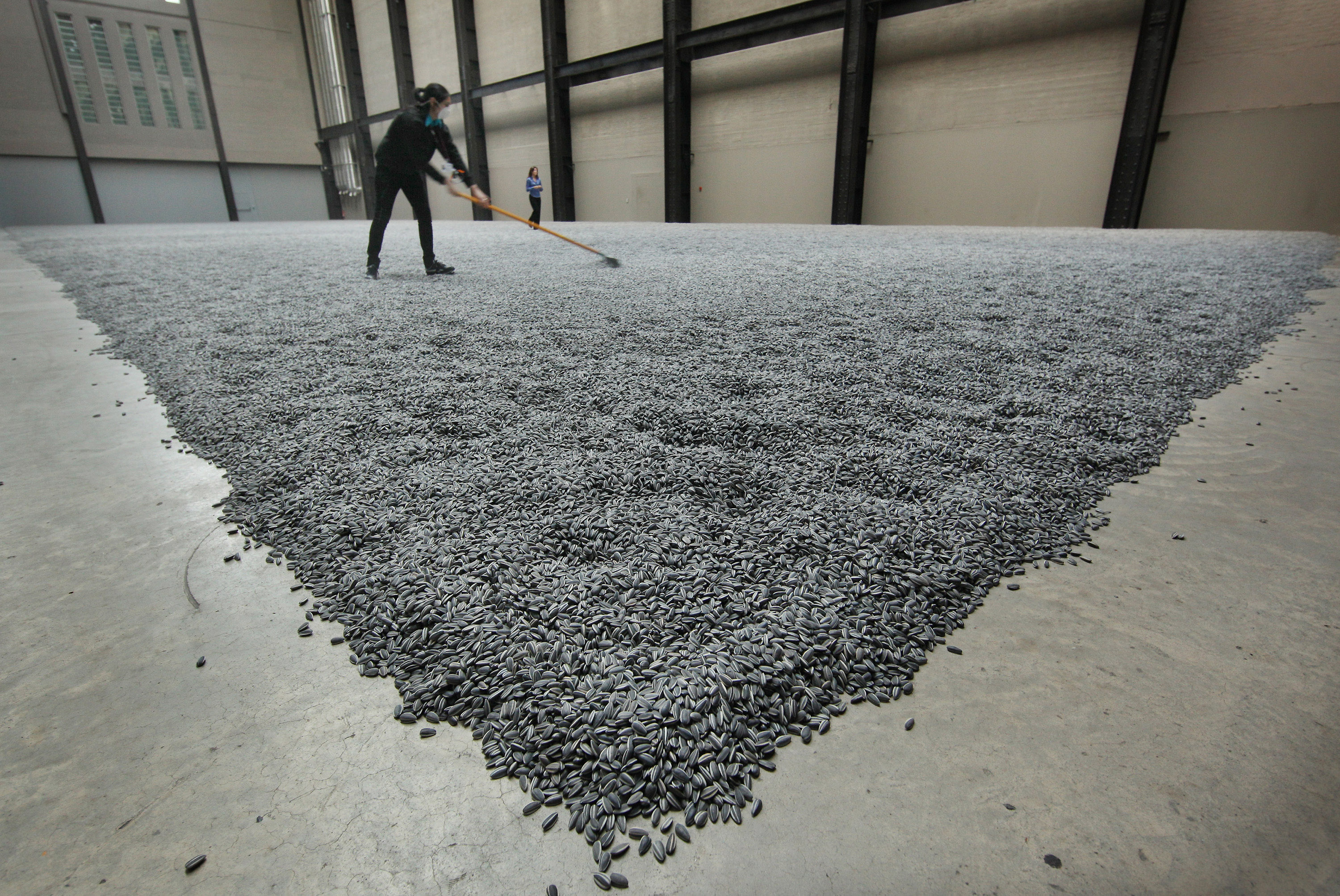 A worker rakes the porcelain "Sunflower Seeds" installation at the Tate Modern.