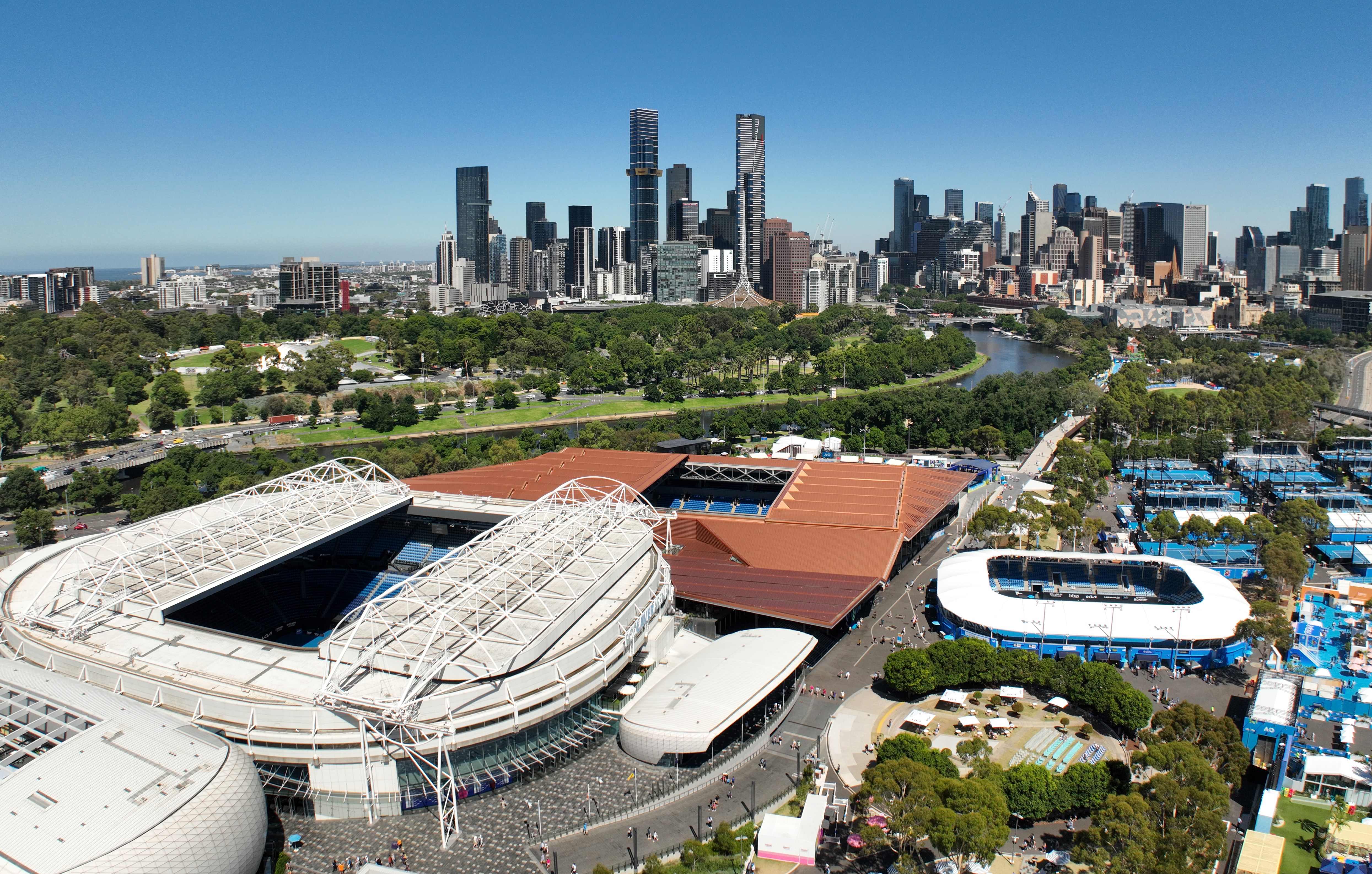 Aerial view of Rod Laver Arena and Melbourne Park with the Melbourne city skyline in the background.