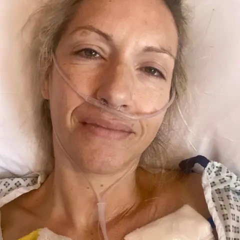 Jessica Mason Jessica wearing a hospital gown, lies in a hospital bed with nasal tubes attached. Her blonde hair is tied back. 